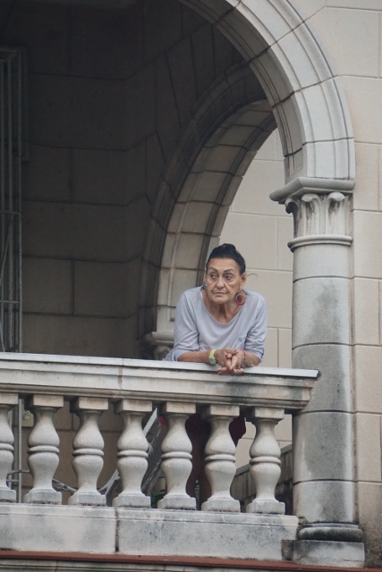 Cuban man leaning out over a balcony.